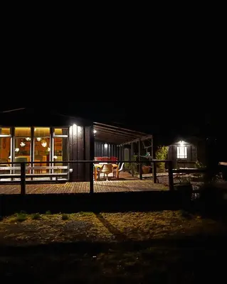 a house at night with a fence in front of it at The Deckhouse, cabin with big deck nr Hay-on-Wye in Rhos-gôch