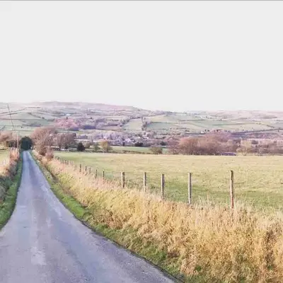 a dirt road with a fence on the side of a field at The Deckhouse, cabin with big deck nr Hay-on-Wye in Rhos-gôch