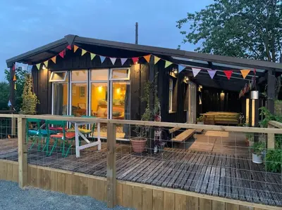 a tiny house with a black roof and a deck at The Deckhouse, cabin with big deck nr Hay-on-Wye in Rhos-gôch