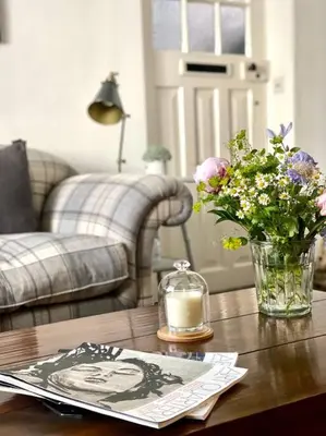 a table with a vase of flowers and a candle at Aragon Cottage in Ludlow