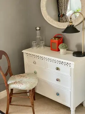 a white dresser with a chair and a mirror at Aragon Cottage in Ludlow