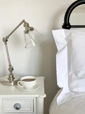 a lamp and a cup of coffee on a bedside table at Aragon Cottage in Ludlow