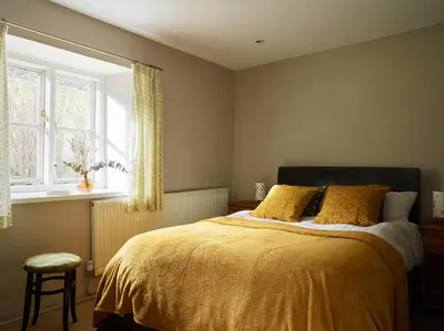 a bedroom with a bed with yellow sheets and a window at The Castle, Capel-y-Ffin, The Black Mountains in Abergavenny