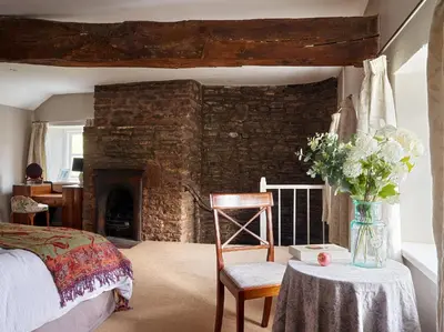 a bedroom with a bed and a table with a vase of flowers at The Castle, Capel-y-Ffin, The Black Mountains in Abergavenny