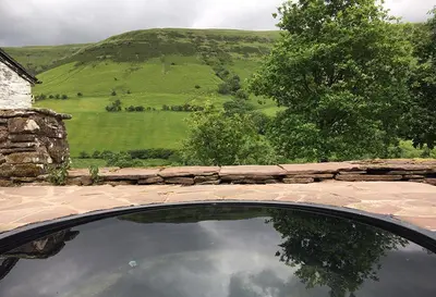 a car parked next to a stone wall with a view of a field at The Castle, Capel-y-Ffin, The Black Mountains in Abergavenny