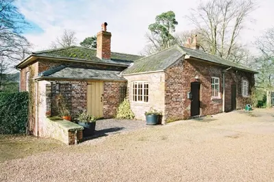 an old brick house with a garage in a yard at The Coach House at Bryngwyn Hall in Llanfyllin
