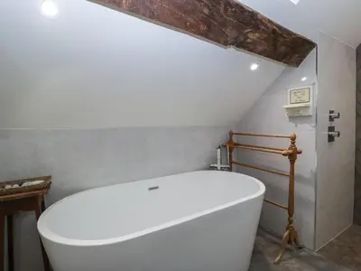 a bathroom with a white tub in a room at Hoarders Cottage in Hereford