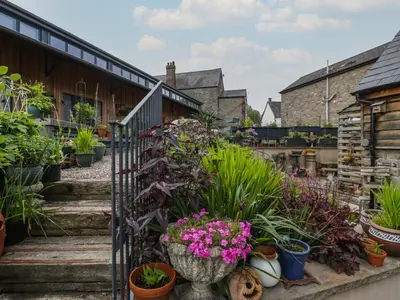 a garden with potted plants on the stairs at Hoarders Cottage in Hereford
