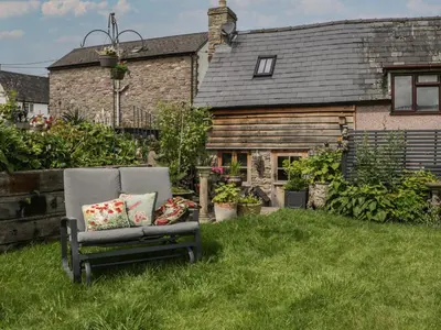 a chair in the grass in front of a house at Hoarders Cottage in Hereford