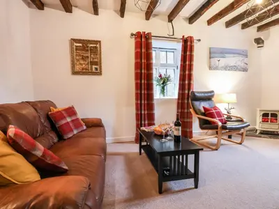 a living room with a brown leather couch and a table at The Brewhouse in Church Stretton