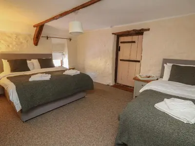 a bedroom with two beds and a door to a garage at Y Cartws in Llanybydder