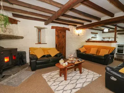 a living room with leather couches and a wood stove at Y Cartws in Llanybydder