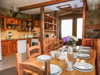 a dining room with a table and a kitchen at Y Felin in Llanybydder