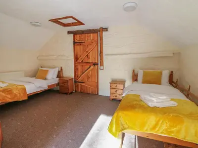 a bedroom with two beds and an open door at Y Felin in Llanybydder