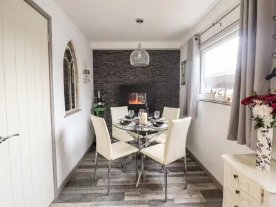 a dining room with a table and chairs and a fireplace at Chalet Forte in Aberdyfi
