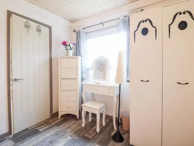a bedroom with a dresser and a chair and a mirror at Chalet Forte in Aberdyfi