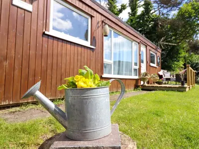 a metal bucket with flowers in it in front of a house at Chalet Forte in Aberdyfi