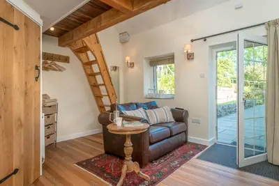 a living room with a leather couch and a staircase at Ty-Gwair-Byrdir in Dyffryn
