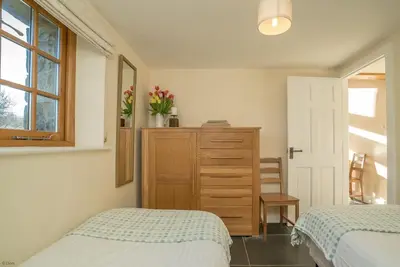 a bedroom with two beds and a dresser and a window at Nant in Dyffryn