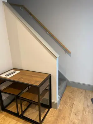 a table in front of a wall with a staircase at Aberystwyth maisonette flat in Aberystwyth