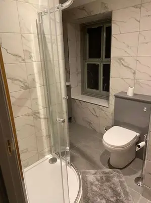 a bathroom with a toilet and a glass shower at Aberystwyth maisonette flat in Aberystwyth