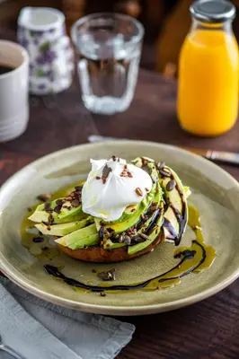 a plate with a stack of pancakes with bananas and whipped cream at The Cedars in Builth Wells