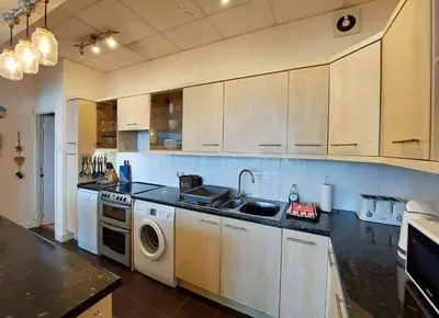 a kitchen with a sink and a washing machine at Beach Front Apartment in Tywyn in Tywyn