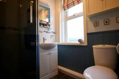 a bathroom with a sink and a toilet and a window at Beach Front Apartment in Tywyn in Tywyn