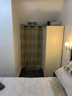 a bedroom with a bed and a plaid shower curtain at Dolgoch Mill House Annexe in Llanfair Caereinion