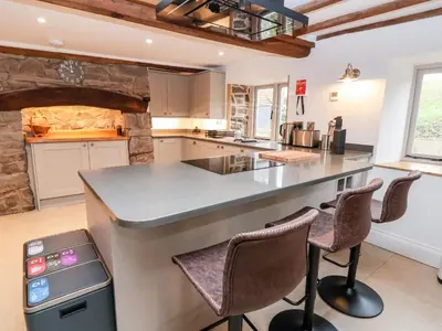 a kitchen with a counter and stools in it at Rockhill Farmhouse in Craven Arms