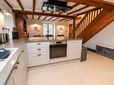 a kitchen with white cabinets and a stove top oven at Rockhill Farmhouse in Craven Arms