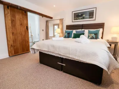 a bedroom with a large bed with a wooden headboard at Rockhill Farmhouse in Craven Arms