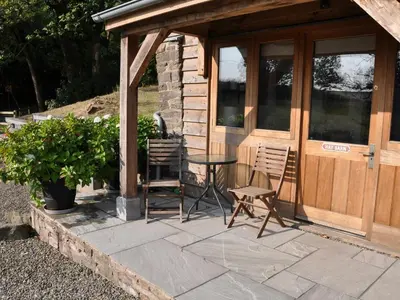 a patio with two chairs and a table in front of a building at Rockhill Farm Hay Barn in Craven Arms