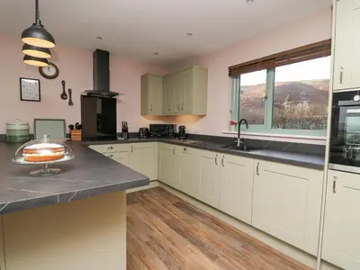 a kitchen with white cabinets and a cake on a counter at Dol Blodau in Llandrindod Wells