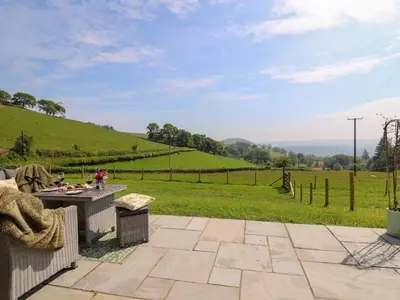 a patio with a table and a view of a field at Dol Blodau in Llandrindod Wells