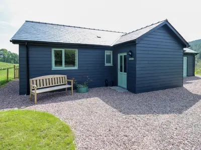a blue shed with a bench in front of it at Dol Blodau in Llandrindod Wells