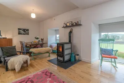 a living room with a wood stove and a table at Brynhoreb in Aberdyfi