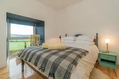 a bedroom with a large bed with a window at Brynhoreb in Aberdyfi