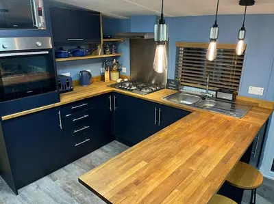 a kitchen with blue cabinets and a wooden counter top at The Cherries - Caer beris holiday park 2 bedroom lodge - No commercial vehicles allowed on site in Builth Wells