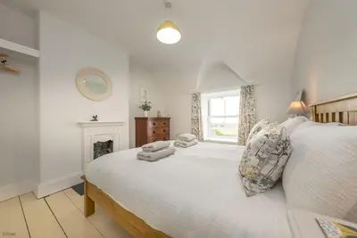 a white bedroom with a large bed and a window at Ty-Newydd-Frongaled in Dyffryn