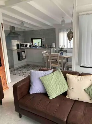 a living room with a brown couch and a kitchen at 7F Cwtch Cymru Lodge, Caer Beris Holiday Park - no commercial vehicles permitted on site in Builth Wells