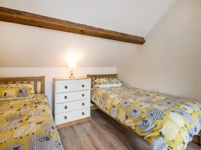 a bedroom with two beds and a dresser at Frondeg Bach in Cross Inn