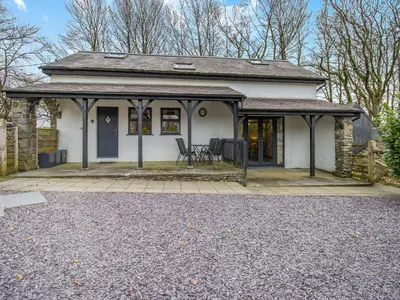 a white house with a porch and a patio at Frondeg Bach in Cross Inn
