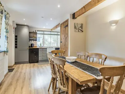 a kitchen and dining room with a wooden table and chairs at Frondeg Bach in Cross Inn
