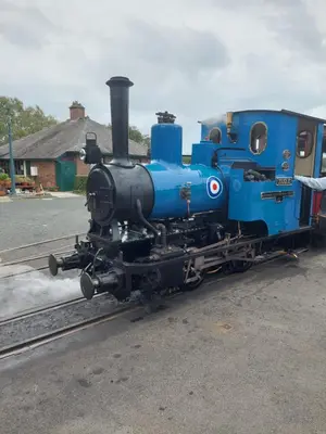 a blue train is sitting on the tracks at The Cosy Pad Glan Y Morfa Bach in Tywyn