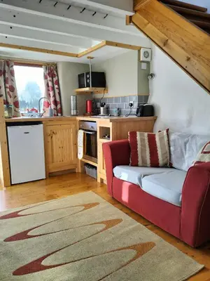 a living room with a red couch in a kitchen at The Cosy Pad Glan Y Morfa Bach in Tywyn