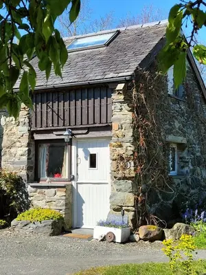 a stone cottage with a white garage door at The Cosy Pad Glan Y Morfa Bach in Tywyn