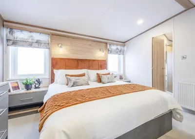 a bedroom with a large bed and two windows at Aber Bay Holiday Park in Aberystwyth