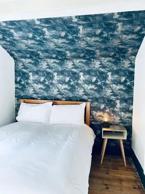 a bedroom with a bed with a blue wall at Dolgellau Grand Heights Apt in Dolgellau