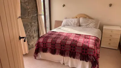 a bedroom with a bed with a checkered blanket at Crogal Stable in New Quay